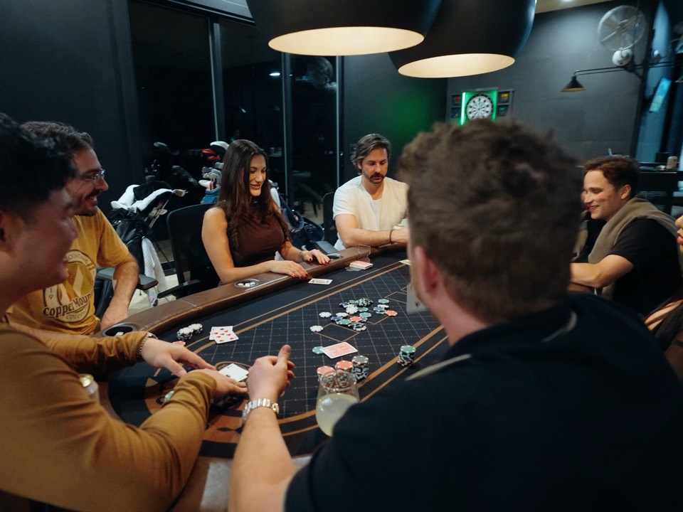 The crew around a poker table with a dealer at the house