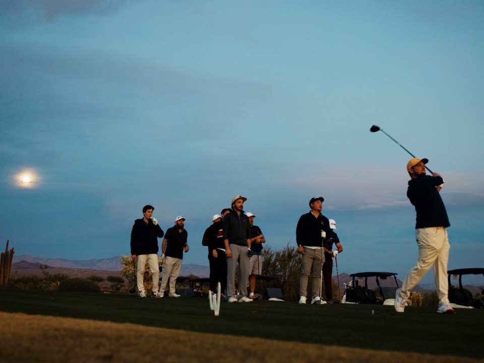 The crew watching a drive from the tee box at dusk
