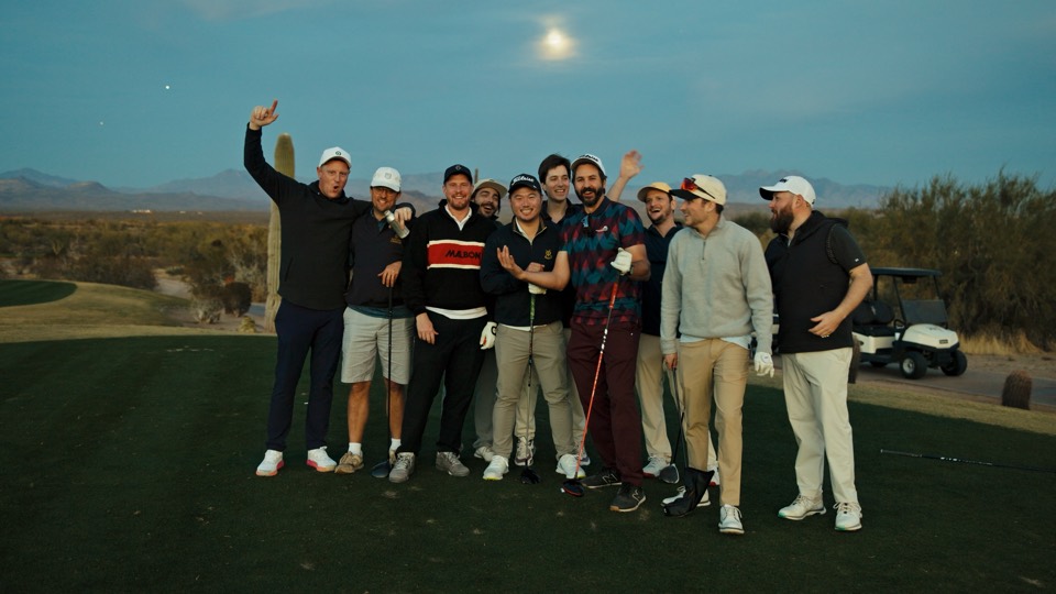 The whole crew cheering on a tee box at dusk